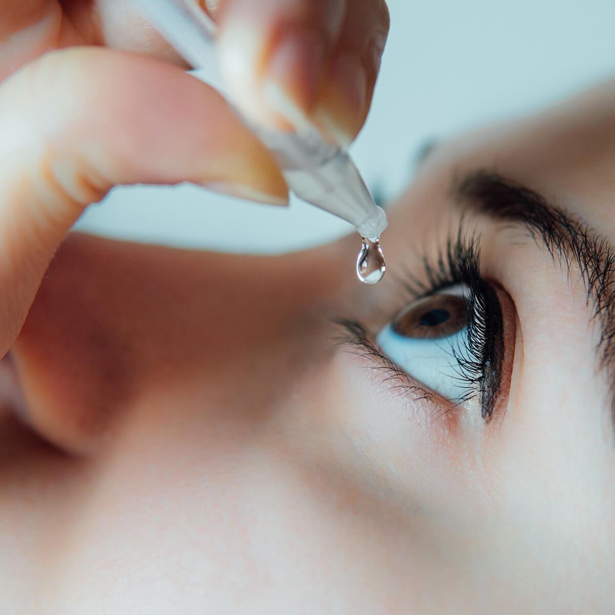 Woman receiving an eyedrop treatment.